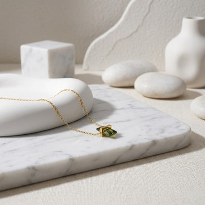 BEHI MILANO Glinka Necklace — green zircon pendant necklace displayed on white marble with stones