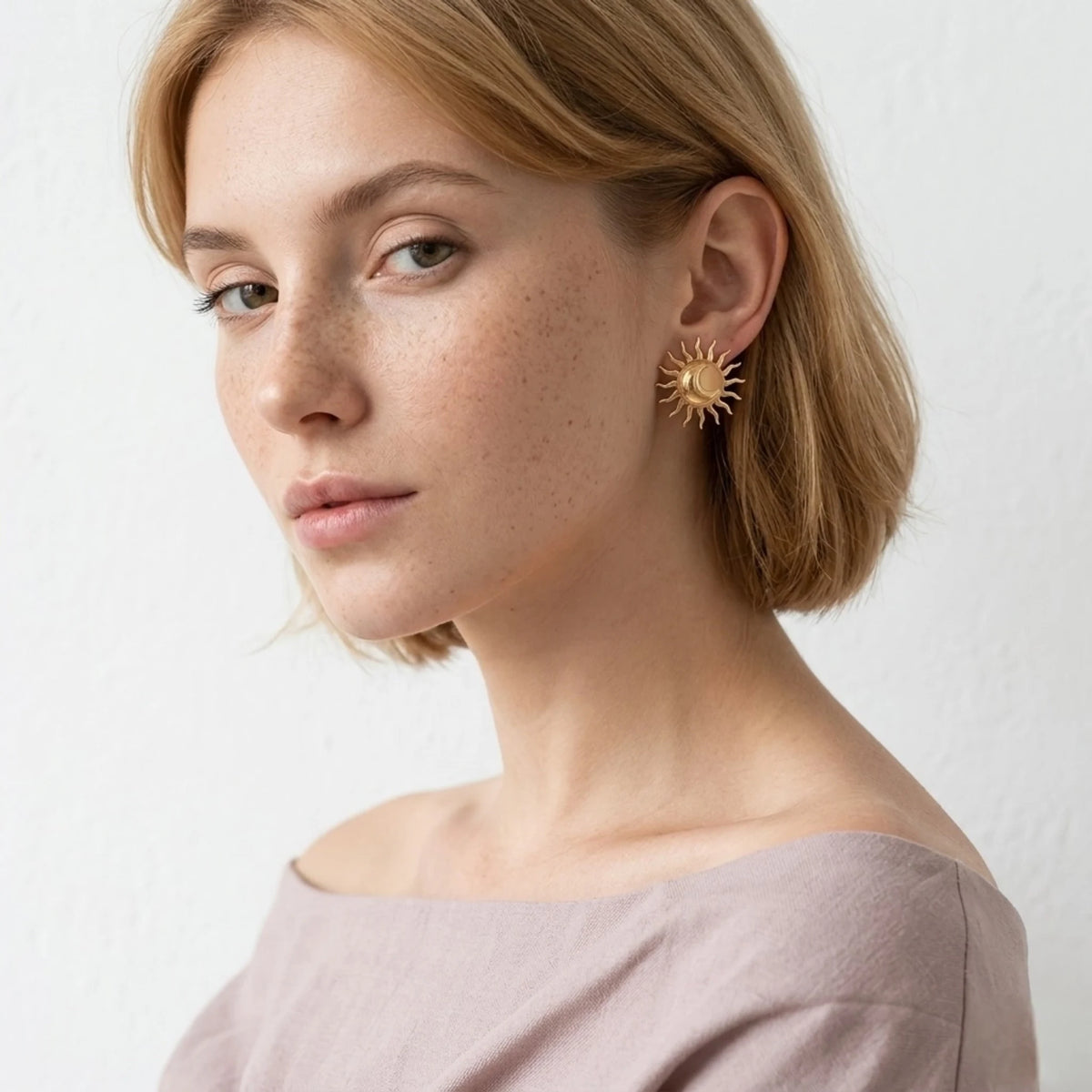 BEHI MILANO Glow Earrings — short blonde model wearing gold sun statement stud in side profile
