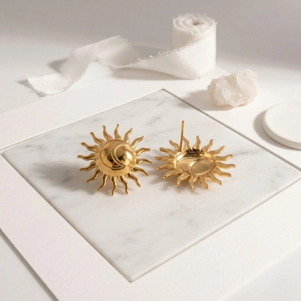 BEHI MILANO Glow Earrings — gold sun studs showing front design and back posts on marble surface
