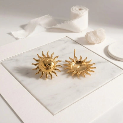 BEHI MILANO Glow Earrings — gold sun studs showing front design and back posts on marble surface