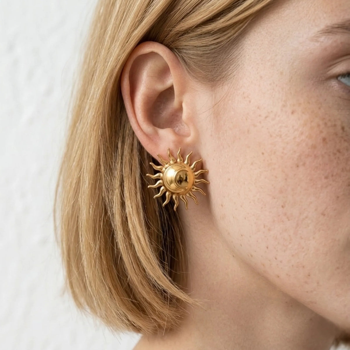 BEHI MILANO Glow Earrings — close-up of model ear wearing 18k gold solar ray statement stud