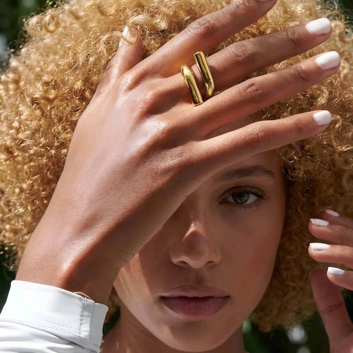 BEHI MILANO Greta Ring — curly hair model wearing gold sculptural crossover ring