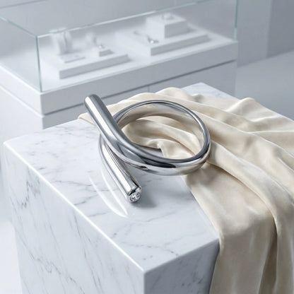 BEHI MILANO Greta Ring — silver crossover ring on marble surface with silk ribbon