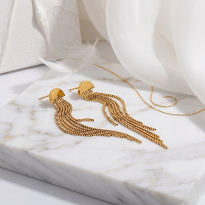 BEHI MILANO Heyley Earrings — gold chain tassel stud earrings displayed flat on white marble tray with fabric