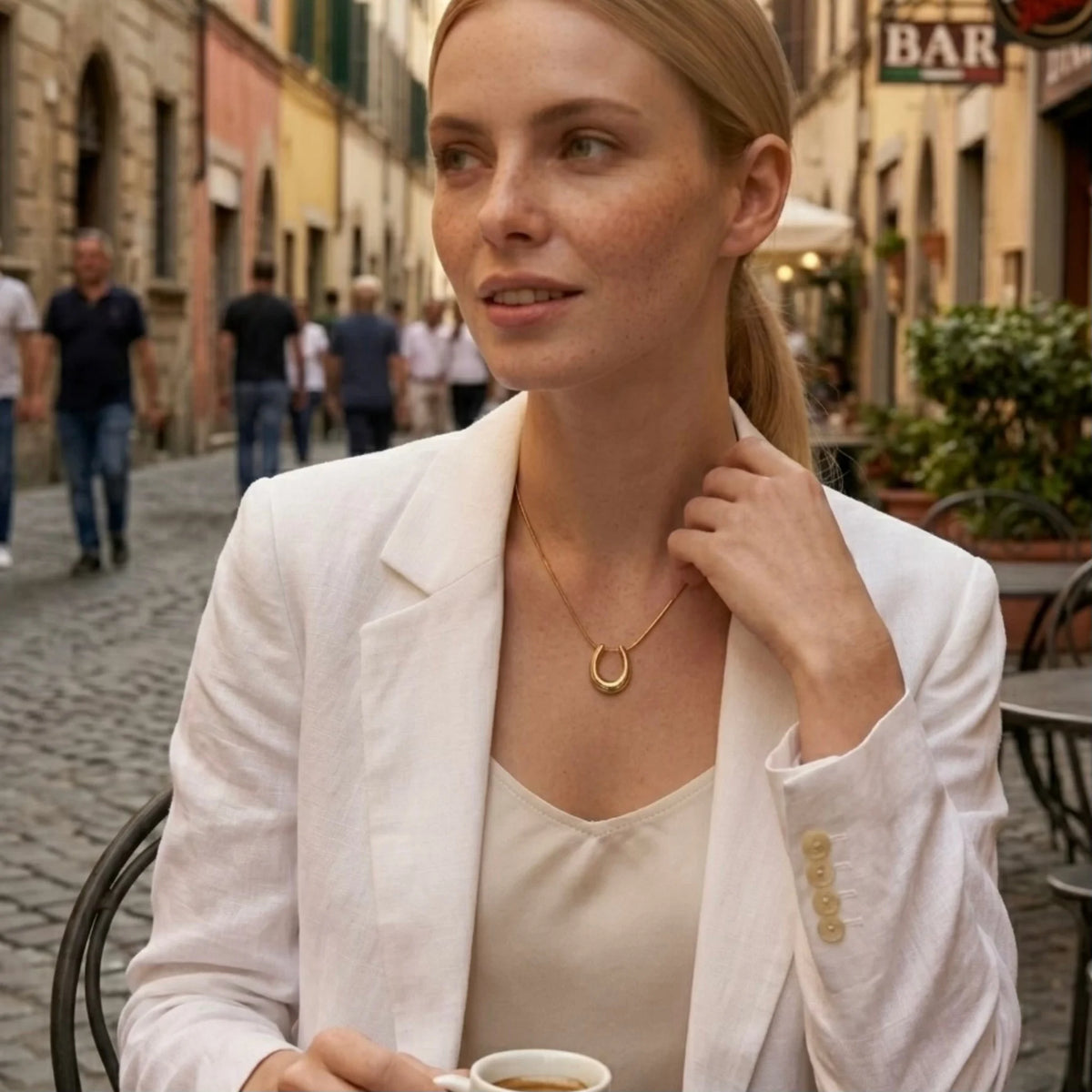 BEHI MILANO Horseshoe Necklace — blonde model walking on Italian street wearing gold horseshoe necklace
