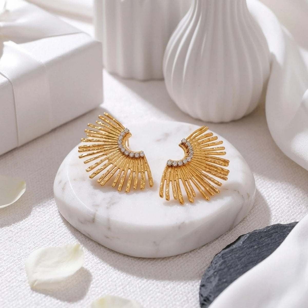BEHI MILANO Indigamond Earrings — gold textured fan studs displayed on white ribbed marble podium