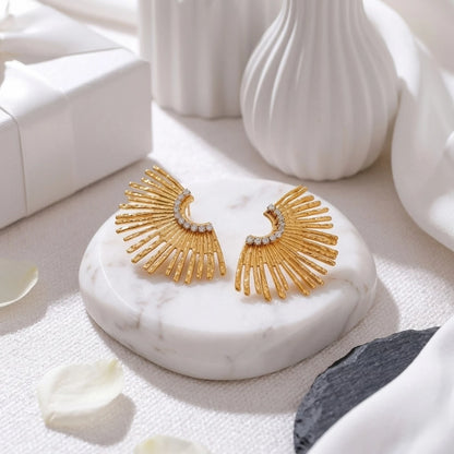 BEHI MILANO Indigamond Earrings — gold textured fan studs displayed on white ribbed marble podium