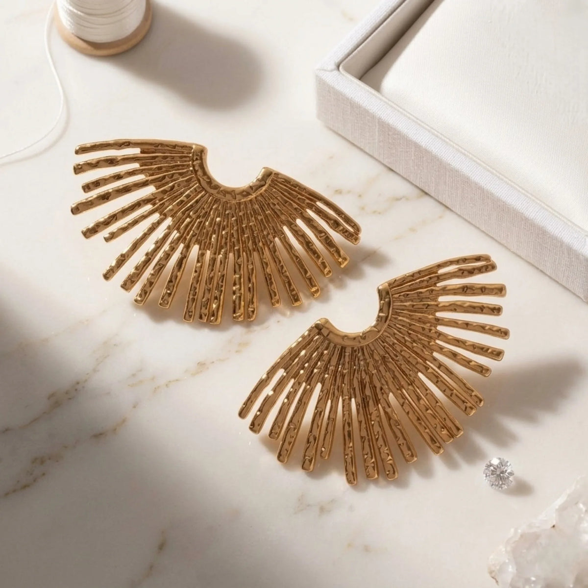 BEHI MILANO Indigo Earrings — detailed close up of textured sunbeam rays on gold fan studs