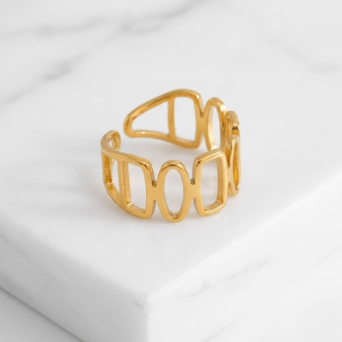 BEHI MILANO Indora Ring — gold geometric band ring displayed on white marble slab