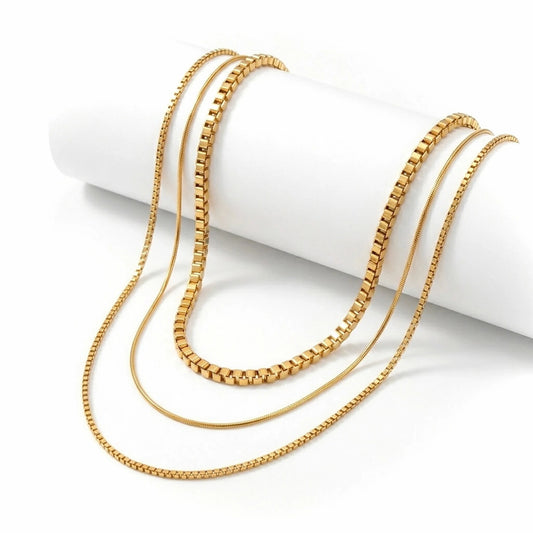 BEHI MILANO Ira Necklace — 18k gold triple layered chain necklace displayed on white cylindrical prop