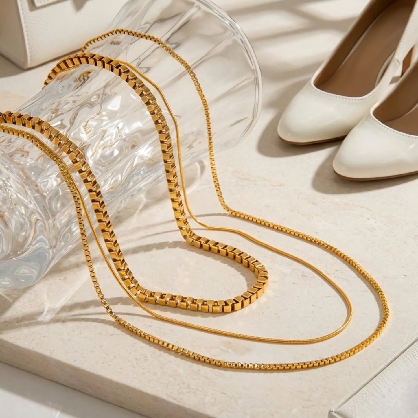 BEHI MILANO Ira Necklace — gold layered chain necklace on textured white silk background