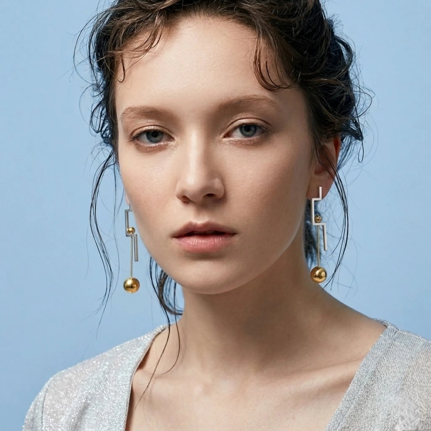 BEHI MILANO Isidora Earrings — portrait of model wearing two tone geometric gold and silver drop earrings