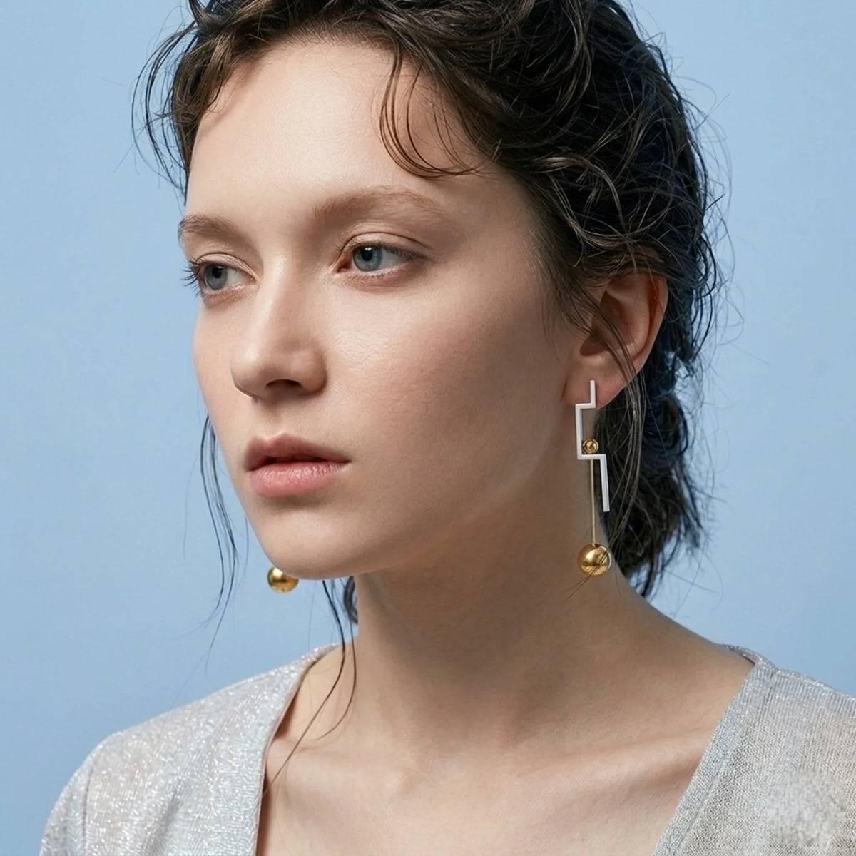 BEHI MILANO Isidora Earrings — side profile view of model wearing two tone linear dangle earrings