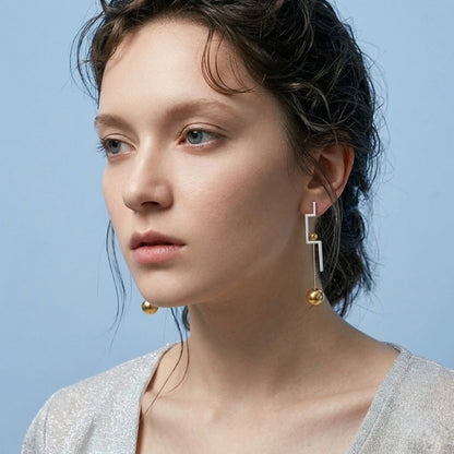 BEHI MILANO Isidora Earrings — side profile view of model wearing two tone linear dangle earrings