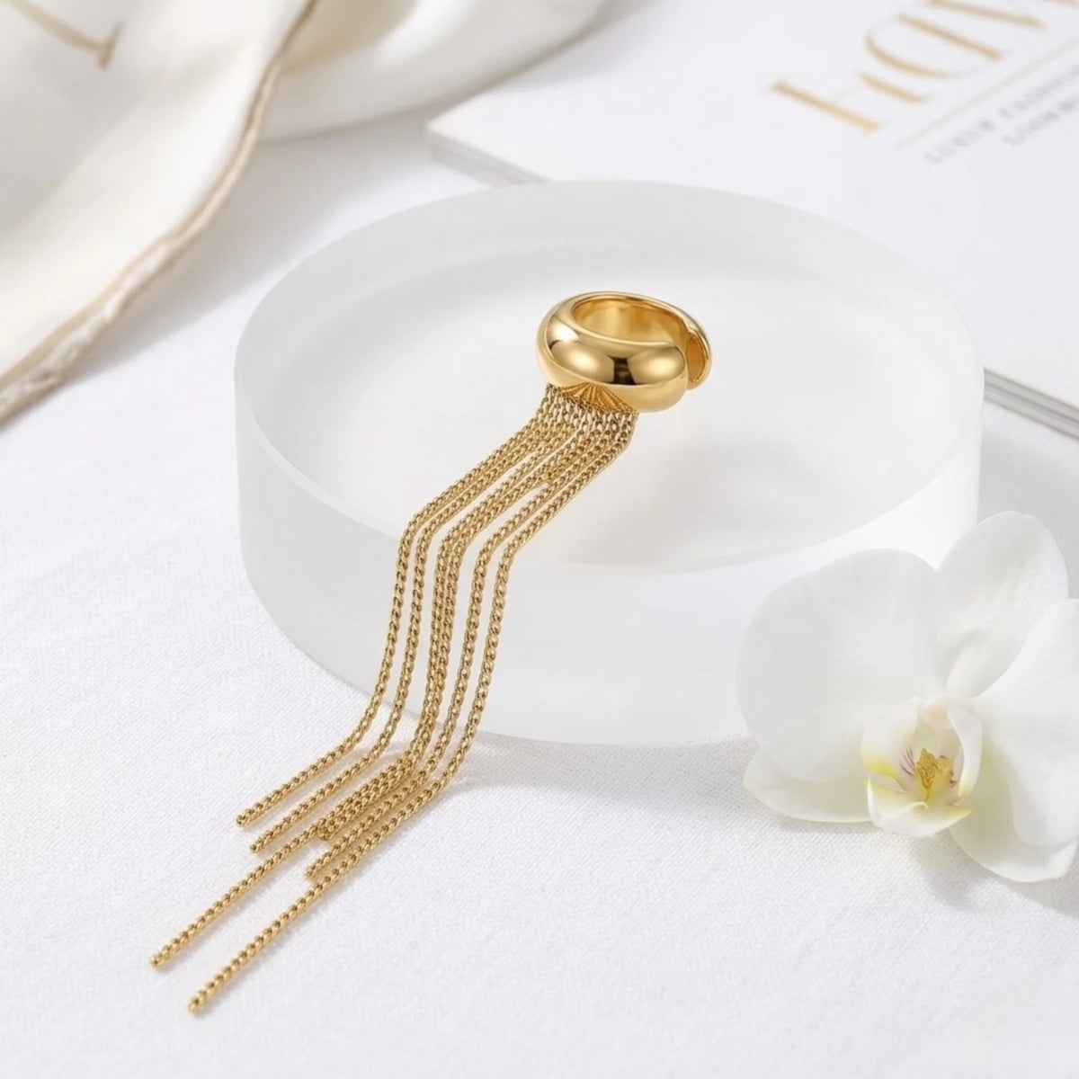 BEHI MILANO Iskra Ear Cuff — 18k gold fringe ear cuff displayed next to white orchid flower