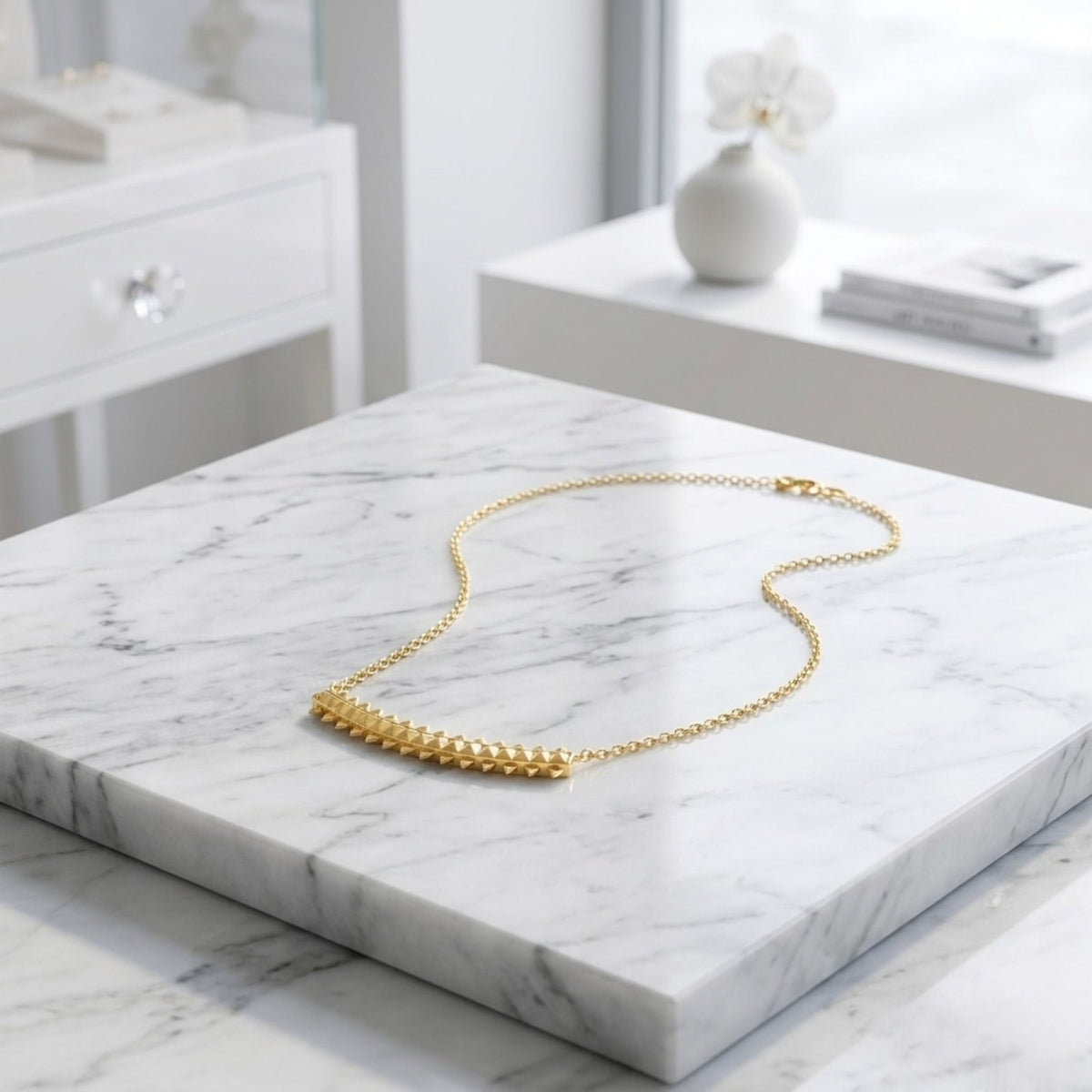 BEHI MILANO Isla Necklace — gold pyramid chain necklace displayed on white marble slab