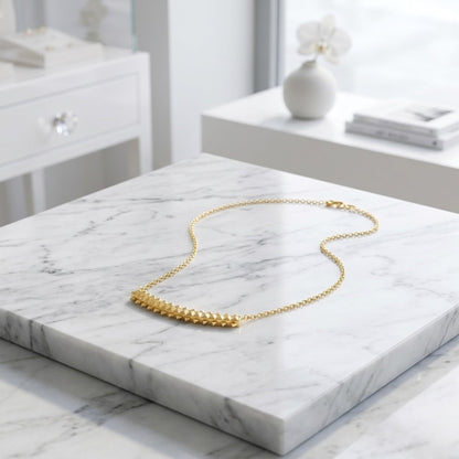 BEHI MILANO Isla Necklace — gold pyramid chain necklace displayed on white marble slab