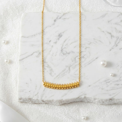 BEHI MILANO Isla Necklace — vertical layout of 18k gold pyramid pendant on white marble backdrop