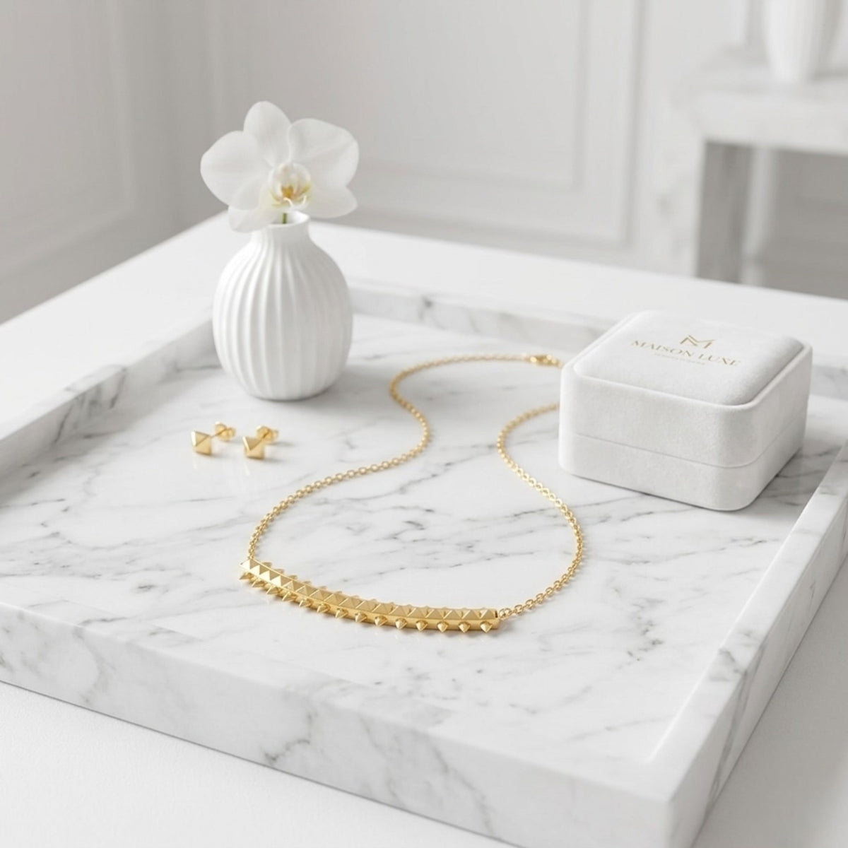 BEHI MILANO Isla Necklace — 18k gold bar pendant necklace resting on marble tray