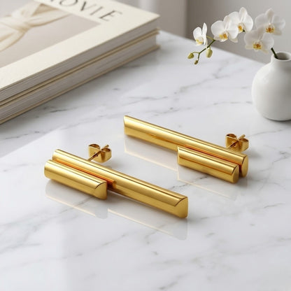 BEHI MILANO Ivana Earrings — pair of 18k gold architectural stud earrings on white marble tray