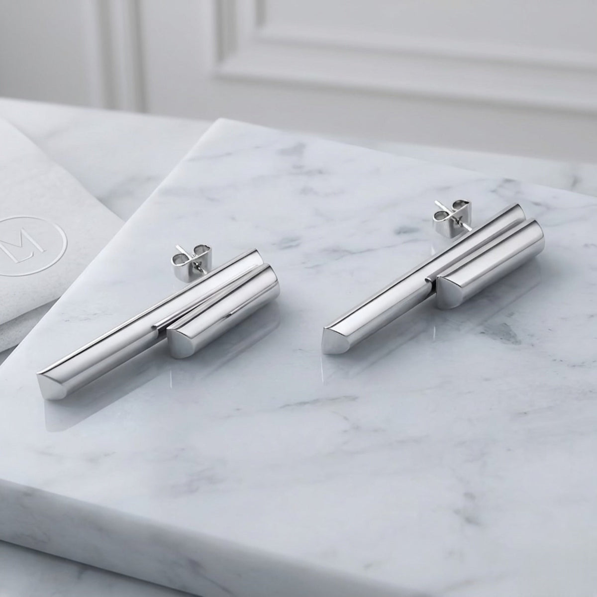 BEHI MILANO Ivana Earrings — silver stainless steel architectural dual bar drop earrings on marble