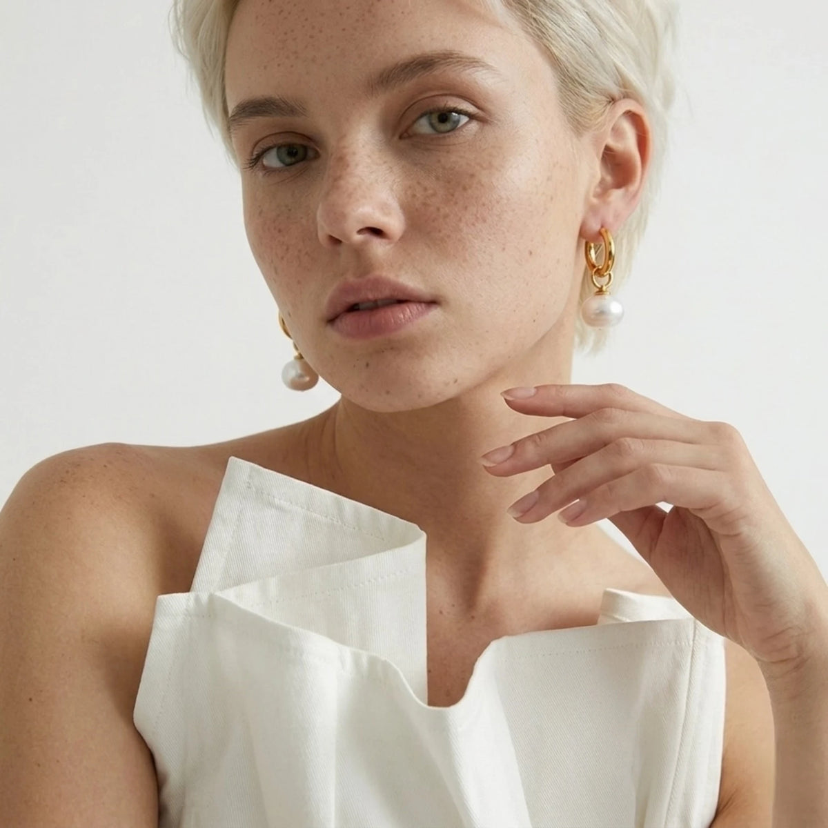 BEHI MILANO Jade Earrings — model in white ruffle top wearing 18k gold pearl drop hoop earrings