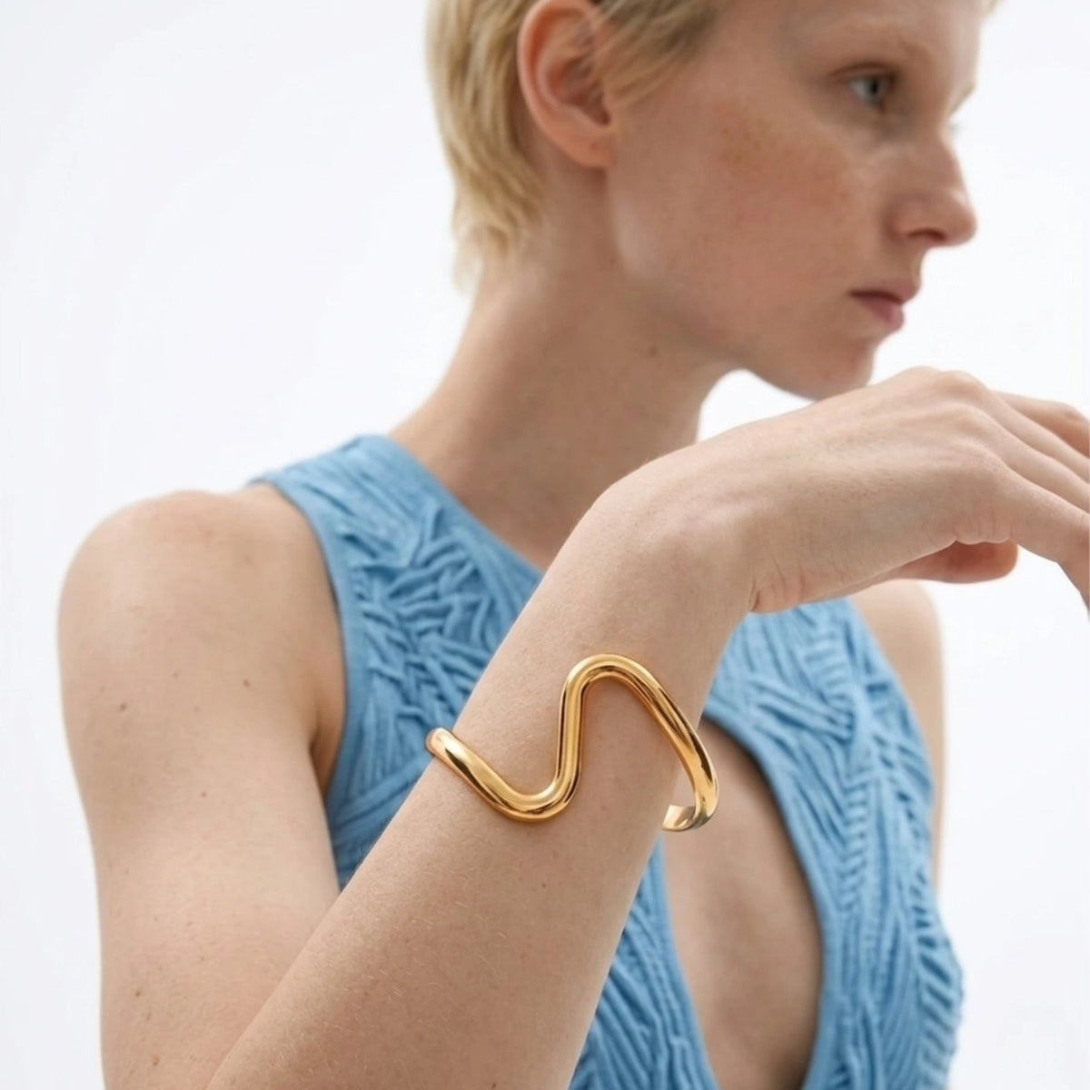 BEHI MILANO Jojo Bracelet — model wearing 18k gold wavy open cuff bangle with blue dress