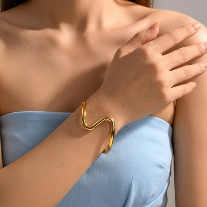 BEHI MILANO Jojo Bracelet — gold sculptural wave cuff styled on wrist