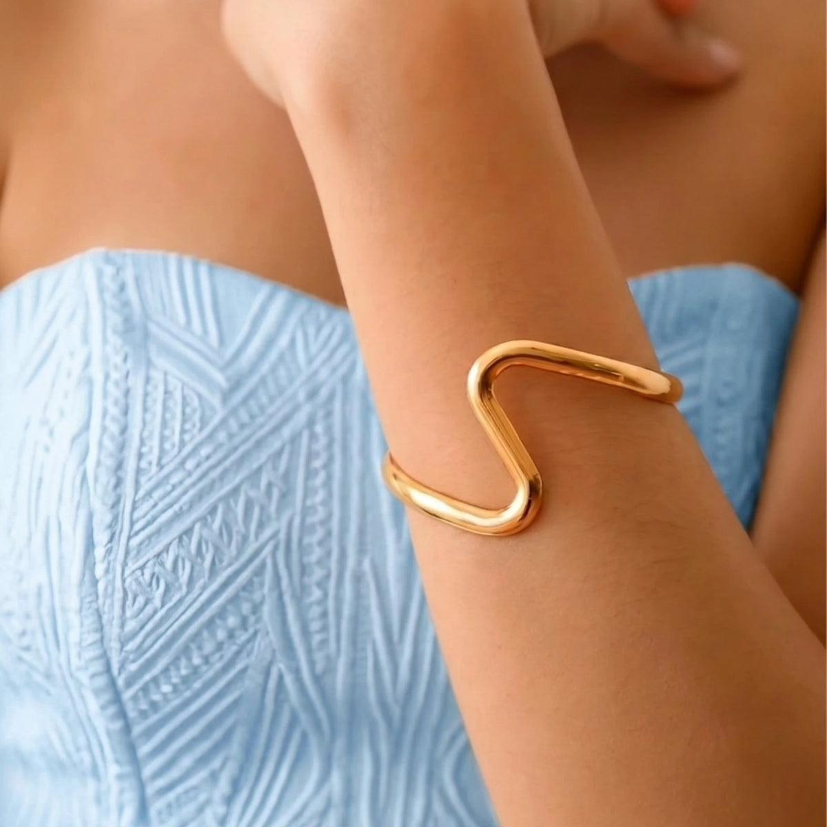BEHI MILANO Jojo Bracelet — close up of gold serpentine wave cuff worn on upper forearm