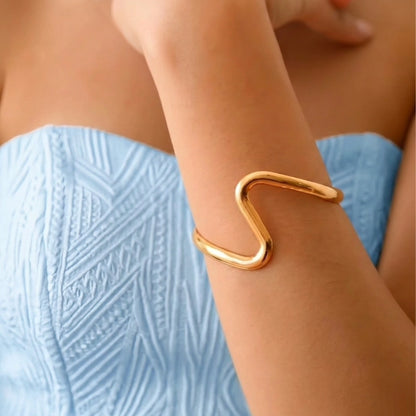 BEHI MILANO Jojo Bracelet — close up of gold serpentine wave cuff worn on upper forearm