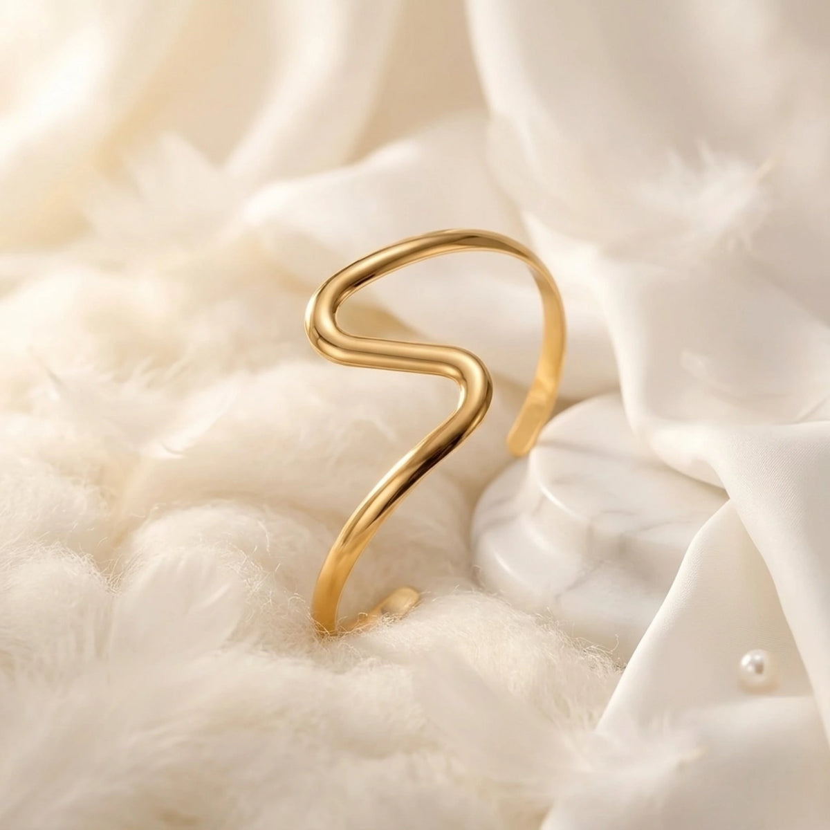 BEHI MILANO Jojo Bracelet — gold wavy cuff standing on white draped silk fabric