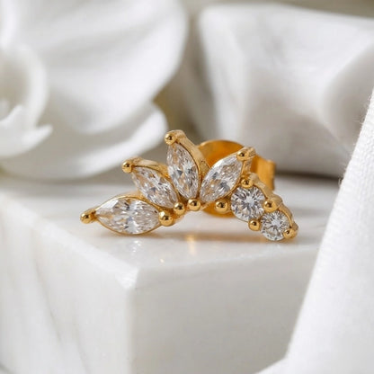 BEHI MILANO Josa Earrings — single gold floral petal crystal stud on white pedestal display