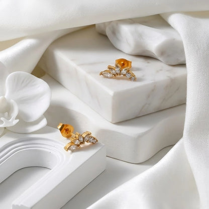 BEHI MILANO Josa Earrings — pair of gold marquise crystal stud earrings on marble surface