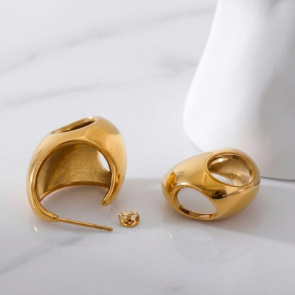 BEHI MILANO Judy Earrings — 18k gold chunky open teardrop hoops resting on white ceramic pedestal