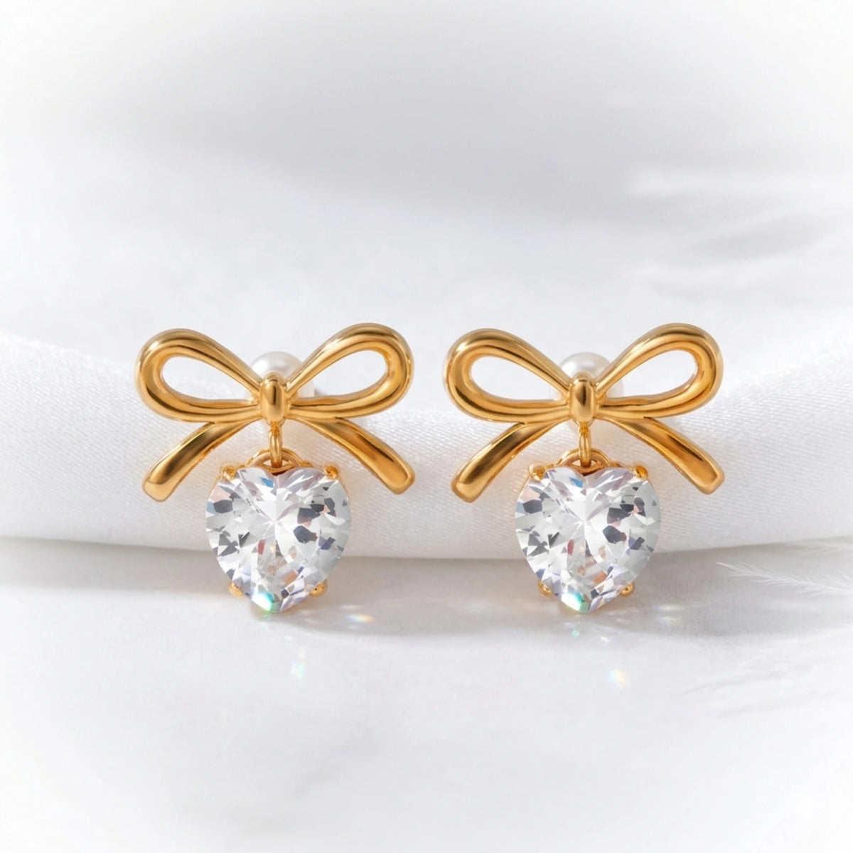 BEHI MILANO Juliette Earrings — gold bow heart crystal earrings on white display with ribbon