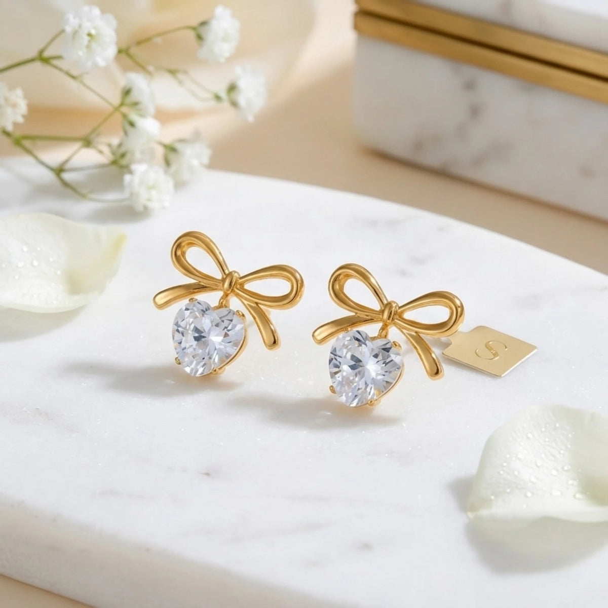 BEHI MILANO Juliette Earrings — 18k gold bow heart crystal drop earrings with white floral backdrop