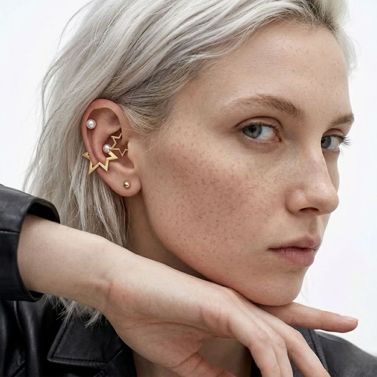 BEHI MILANO Kaia Earrings — platinum blonde model wearing gold star pearl earrings with black leather jacket