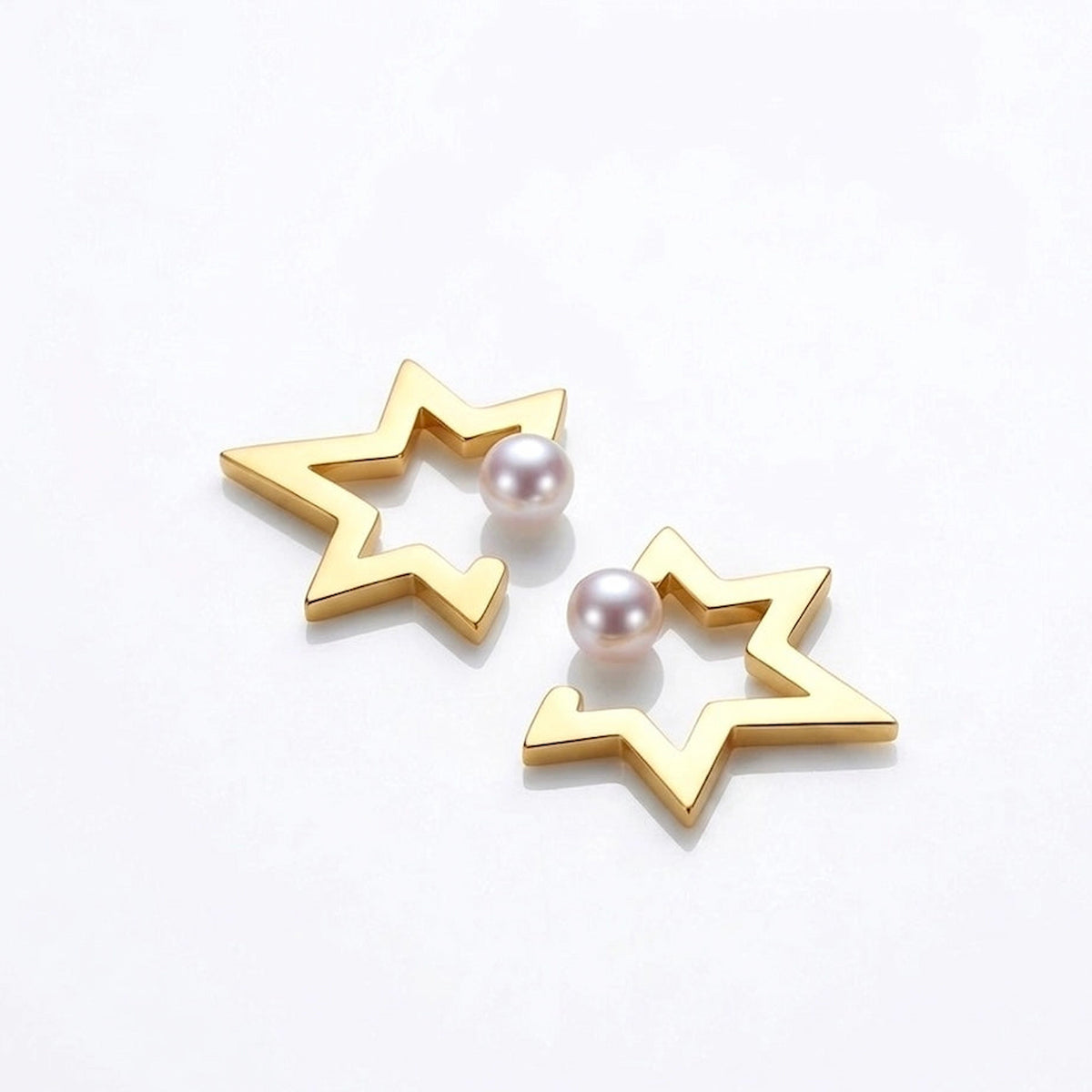 BEHI MILANO Kaia Earrings — gold star outline studs with pearl center on white display block