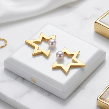 BEHI MILANO Kaia Earrings — 18k gold star pearl studs resting on white ceramic pedestal