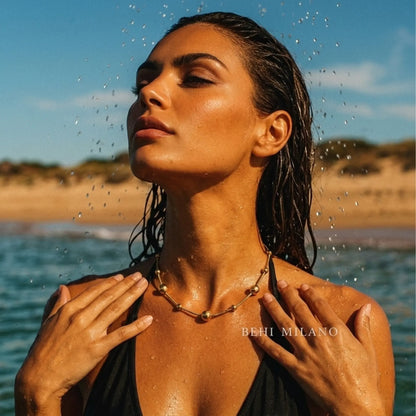 BEHI MILANO Kassia Necklace — beach lifestyle model wearing gold sphere bead necklace in golden hour sun