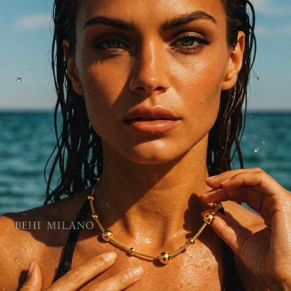 BEHI MILANO Kassia Necklace — frontal portrait of model wearing 18k gold beaded chain necklace in ocean