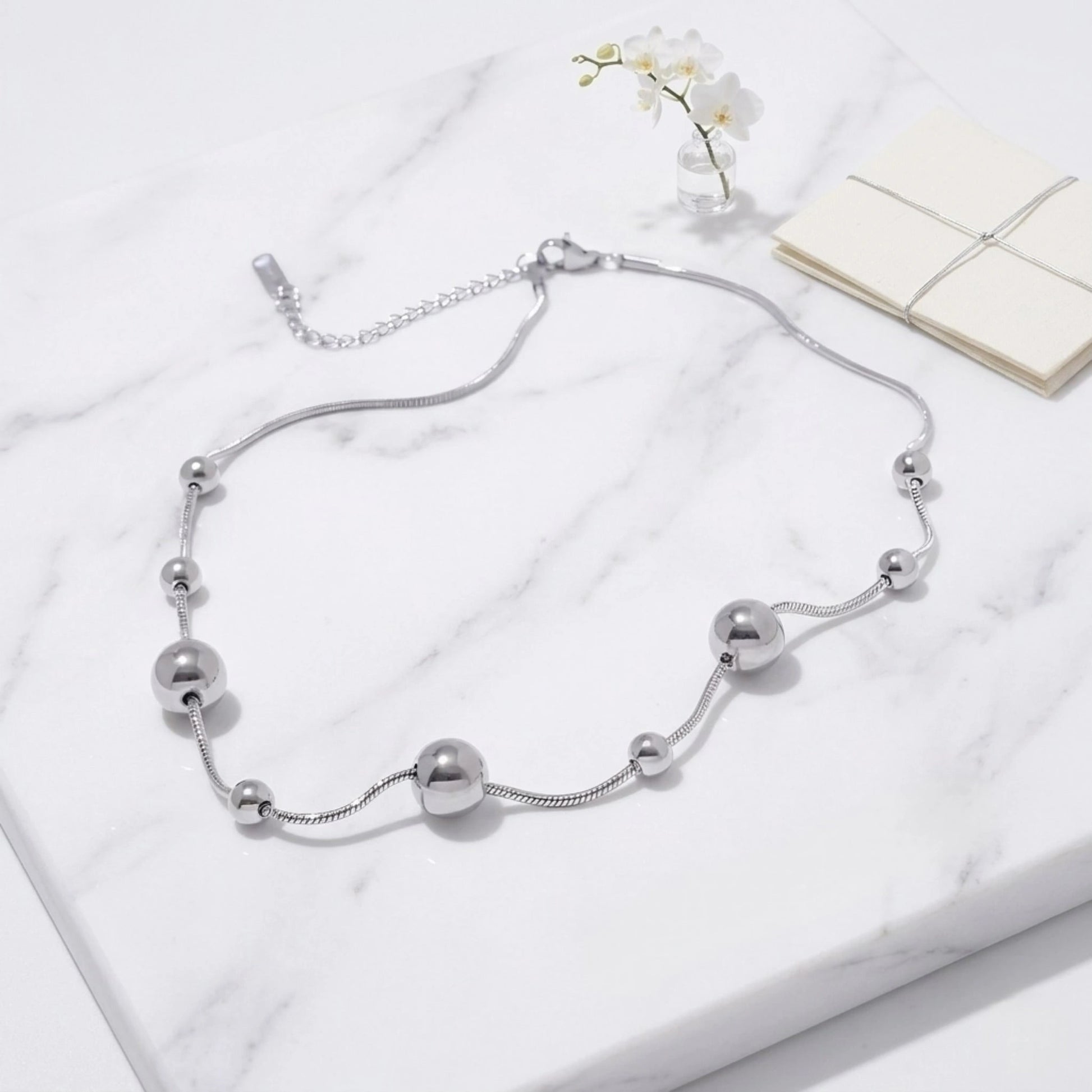 BEHI MILANO Kassia Necklace Silver — stainless steel silver sphere bead choker on marble platform