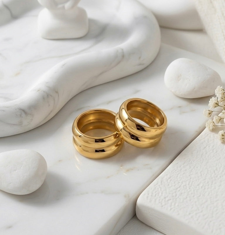 BEHI MILANO Katrina Ring — pair of gold double band dome rings on white marble coaster