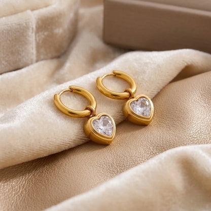 BEHI MILANO Lana Earrings — gold heart crystal drop huggie earrings with signature jewelry box on beige silk
