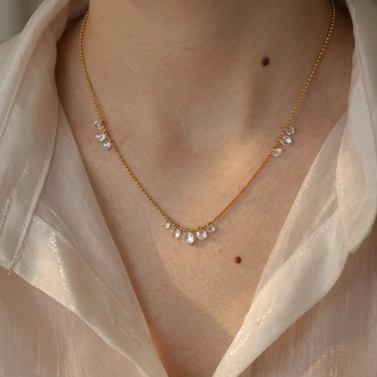BEHI MILANO Larissa Necklace — close-up detail of gold crystal cascade chain on model's neckline