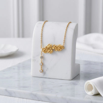 BEHI MILANO Lauris Necklace — gold floral Y-drop necklace displayed on elegant white jewelry bust