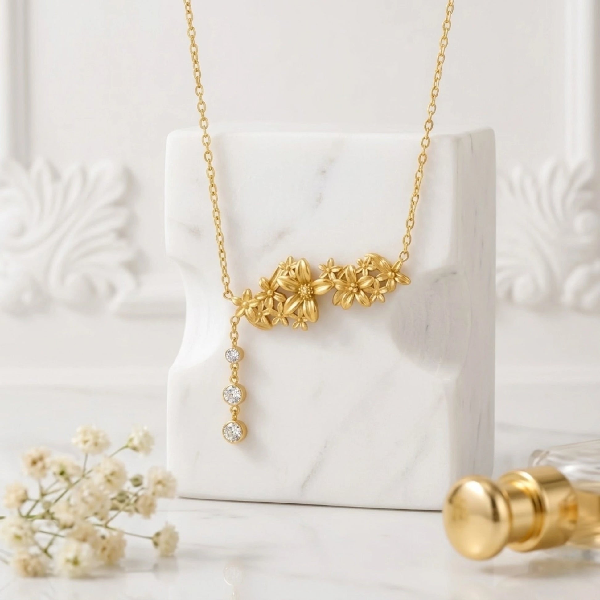 BEHI MILANO Lauris Necklace — gold floral drop necklace styled on white marble block with pearl accents