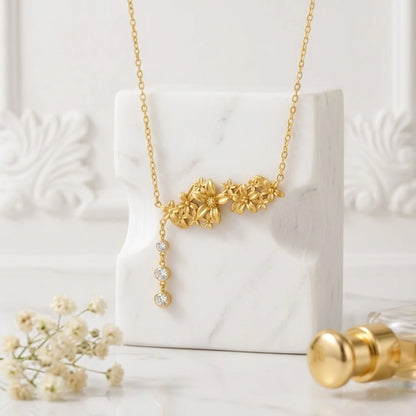 BEHI MILANO Lauris Necklace — gold floral drop necklace styled on white marble block with pearl accents