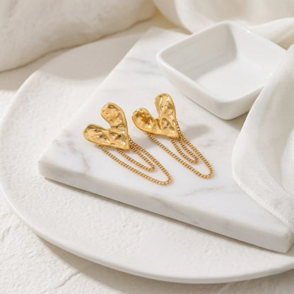 BEHI MILANO Ledda Earrings — gold heart chain drop earrings displayed on white ceramic tray