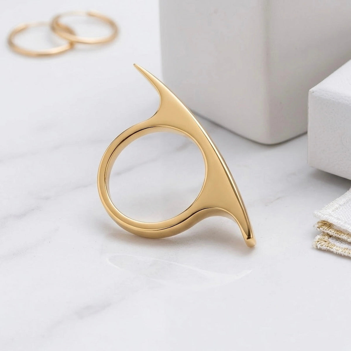 BEHI MILANO Leena Ring — gold pointed ring arranged on white geometric display blocks